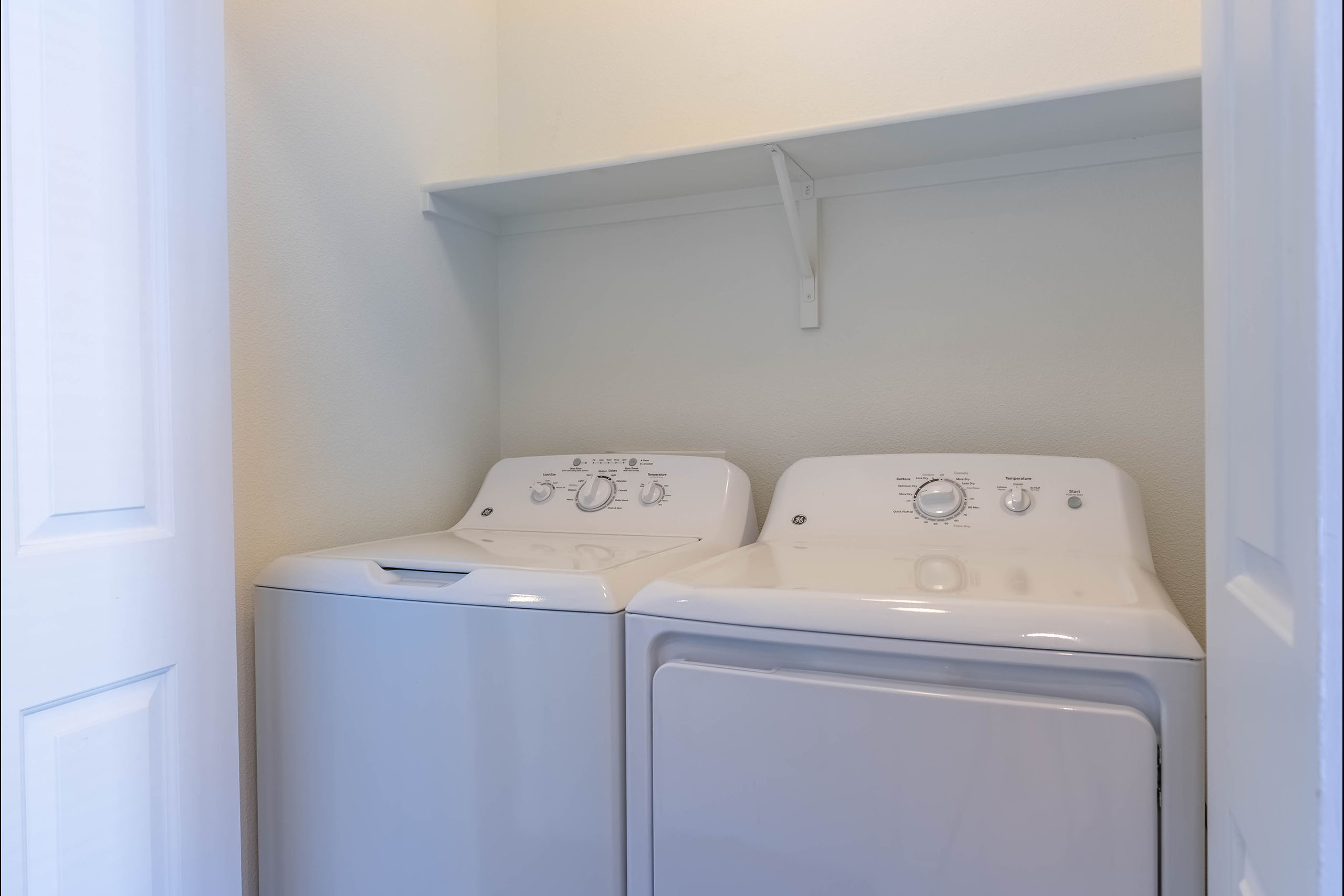 Two white front loading washing machines in a small laundry room.