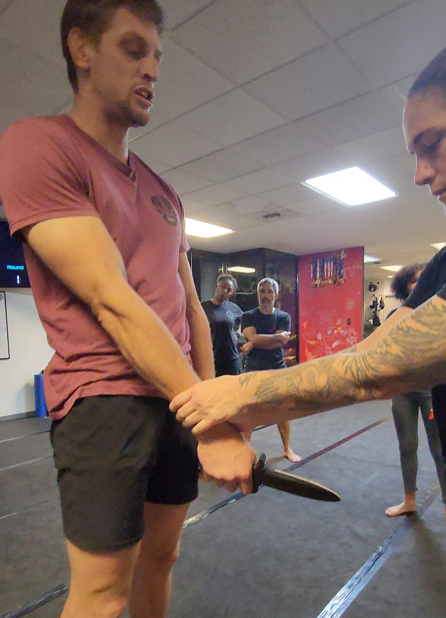 An instructor demonstrating a knife defense and disarm during a weapons defense class.