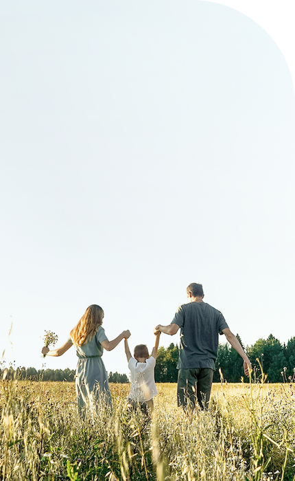A family walking through a field hand in hand.