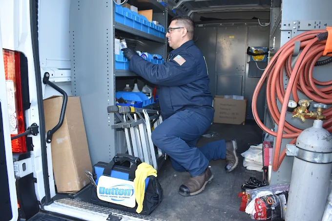 Dutton Plumbing, Cooling & Heating expert inside the company's service van 