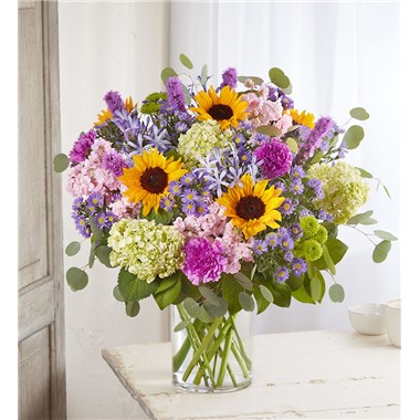 A bouquet this radiant is sure to receive glowing reviews. Part of our Simply Spectacular Collection, showcasing unique varieties and exceptional designs, this luxurious arrangement features a loose, flowy mix of blue agapanthus, green mini hydrangea and golden sunflowers, blended with purple-hued blooms and natural accents. Available in five sizes, it’s a gift of undeniable beauty and fresh-from-the-garden style.