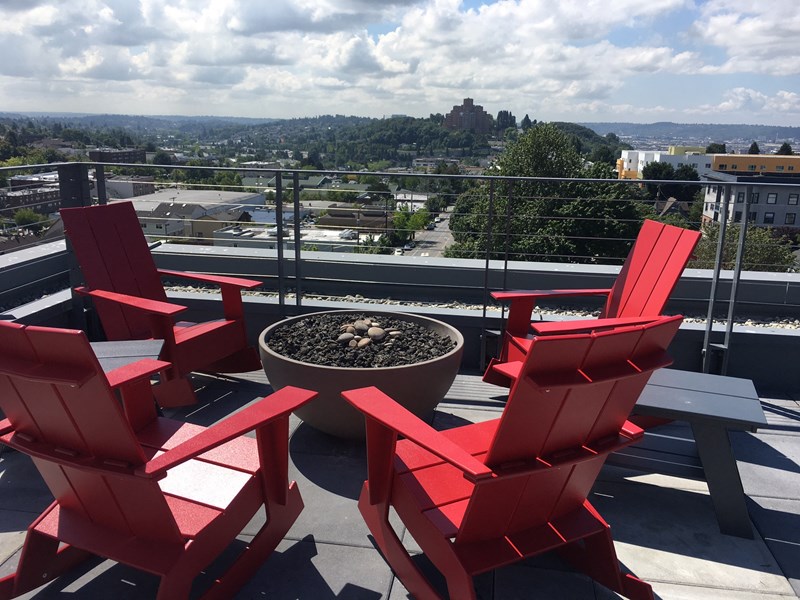 Red adirondack chairs surrounding a fire pit on the rooftop at Decibel on 12th