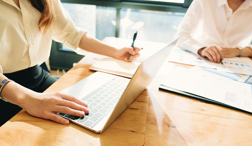 Close-up of two people collaborating at a desk.