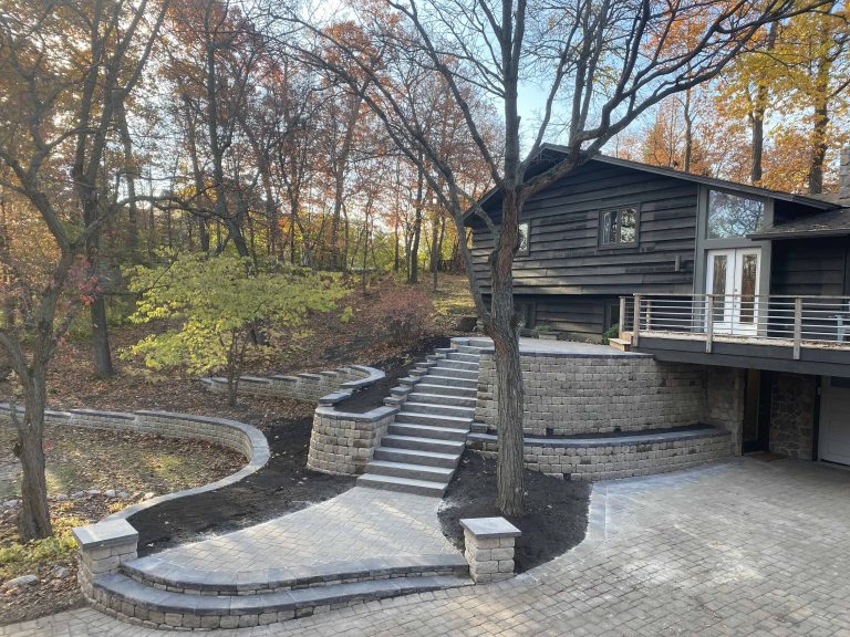 A complete outdoor transformation, paver driveway, curved retaining walls, and stone steps that blend beautifully with the natural surroundings.