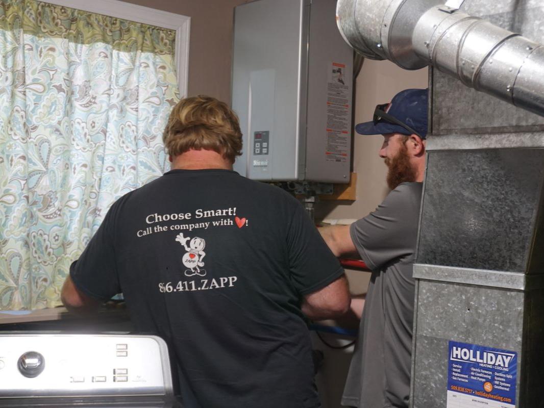 Plumbers inspect the installation of a tankless water heater