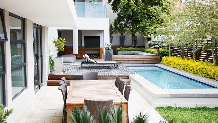 A beautifully landscaped and modern backyard with an inground pool.