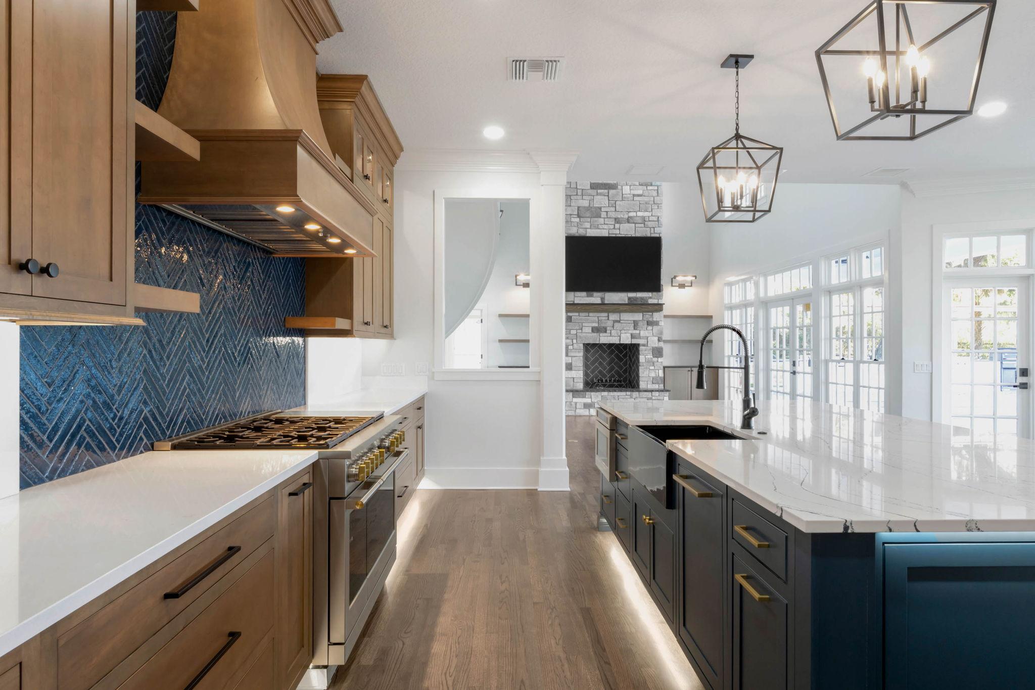 Custom-built luxury kitchen featuring a large quartz island, custom wood cabinetry, designer lighting, and open-concept layout by custom home builders in Central Florida.