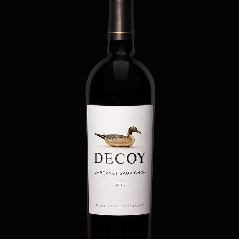 A bottle of Decoy Cabernet Sauvignon 2018 wine from Duckhorn Portfolio, featuring a label with a realistic illustration of a duck decoy.