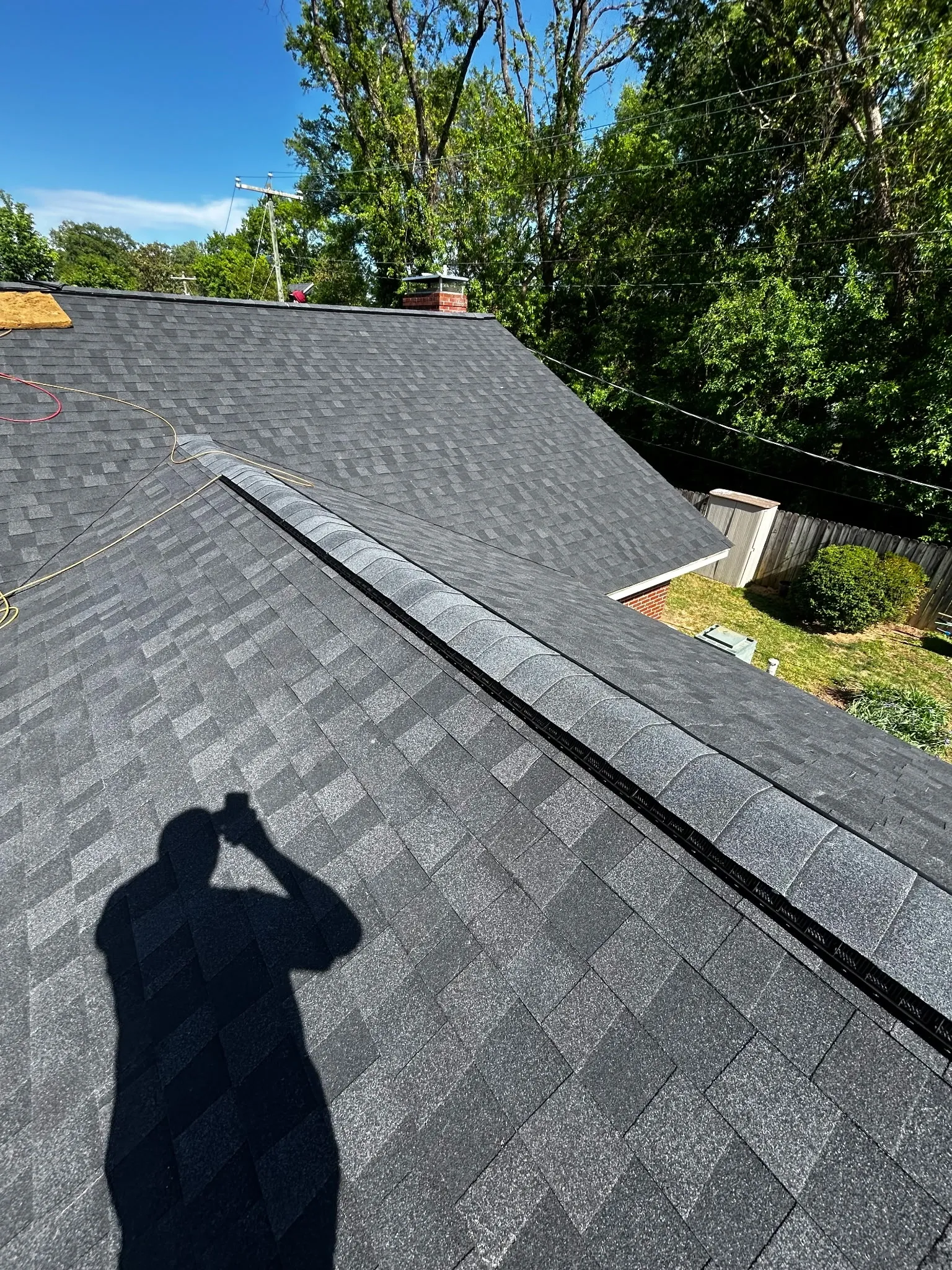 Completed architectural-shingle roofing with ridge-cap installation. 