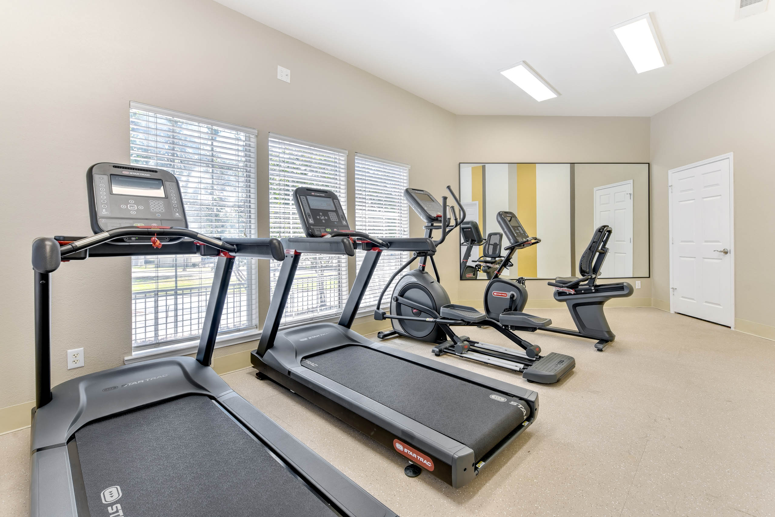 A spacious gym with treadmills, elliptical machines, and other exercise equipment.