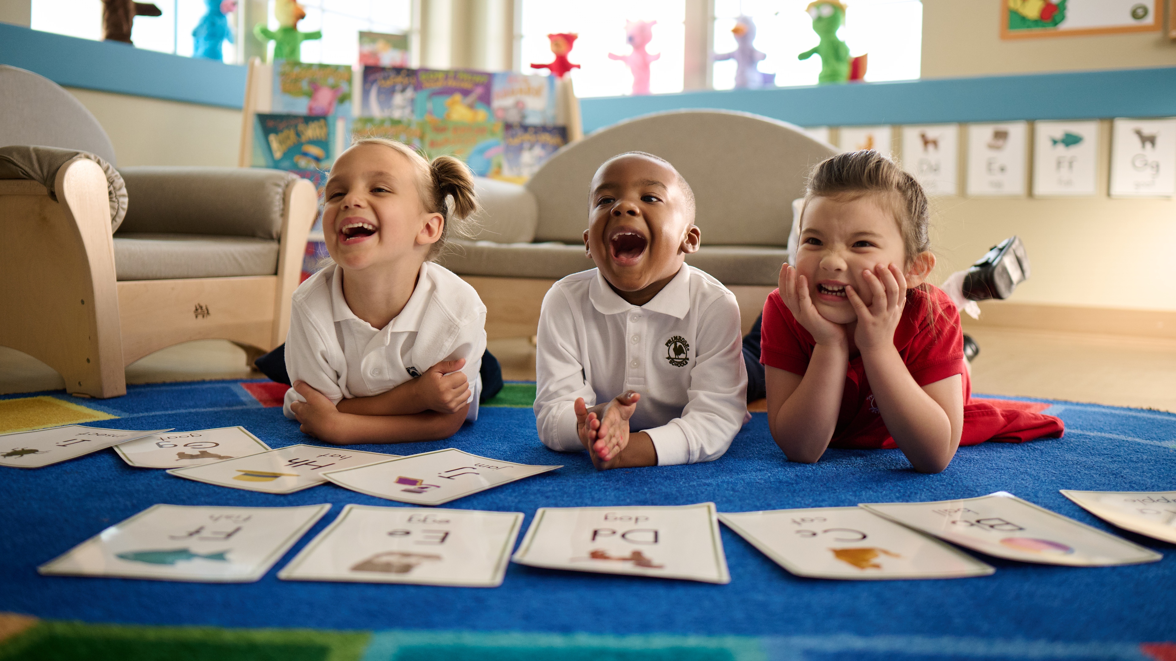 Primrose Schools preschool children laughing during alphabet flashcard activity in bright, engaging classroom