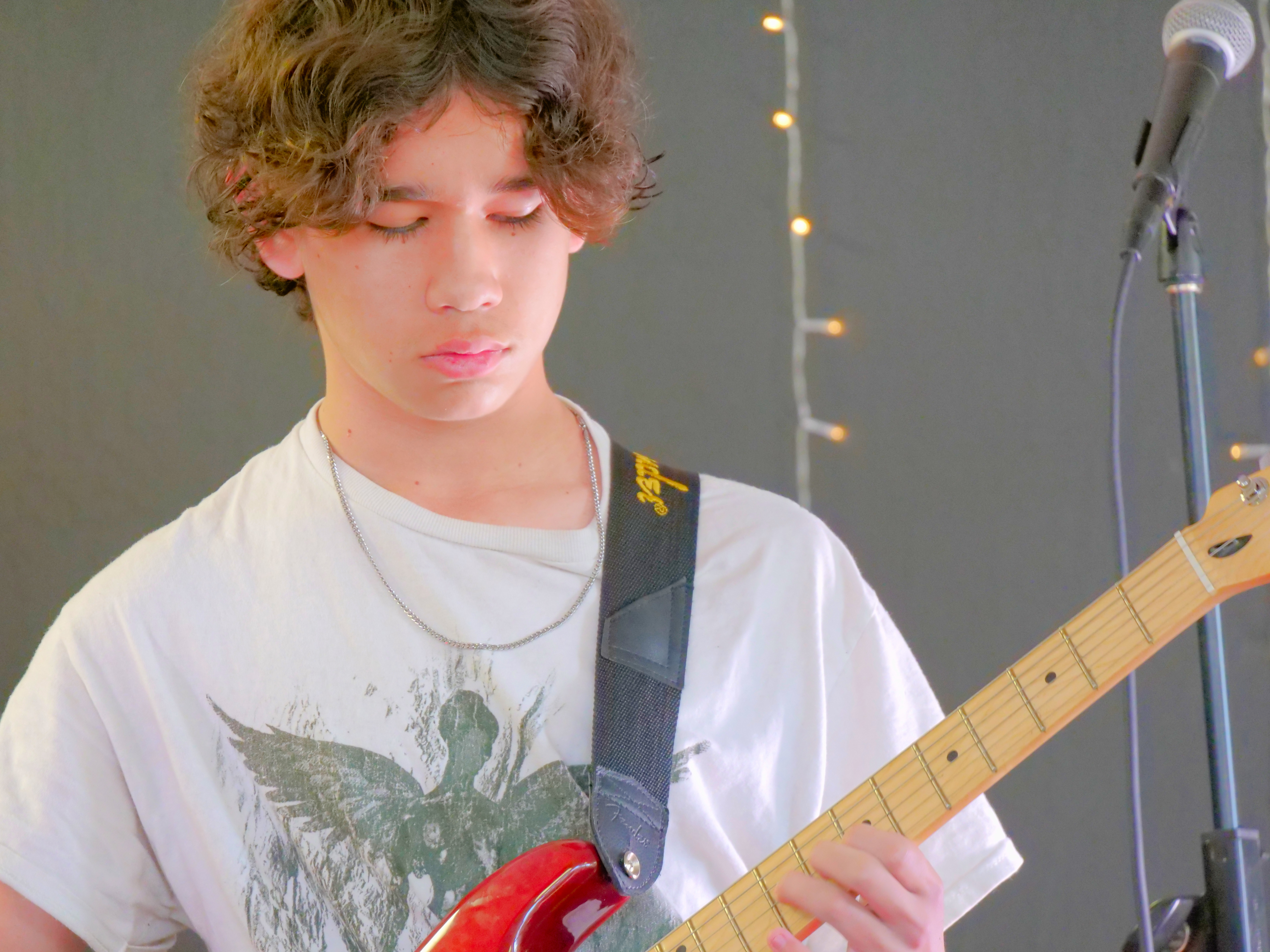Student guitarist performing live during a beNatural Music student showcase and performance training event.