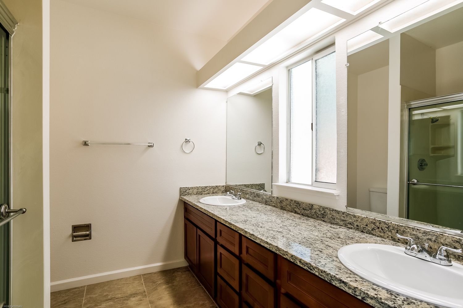 Bathroom with dual vanity sinks, granite countertop and bright lighting at Invitation Homes Northern CA.