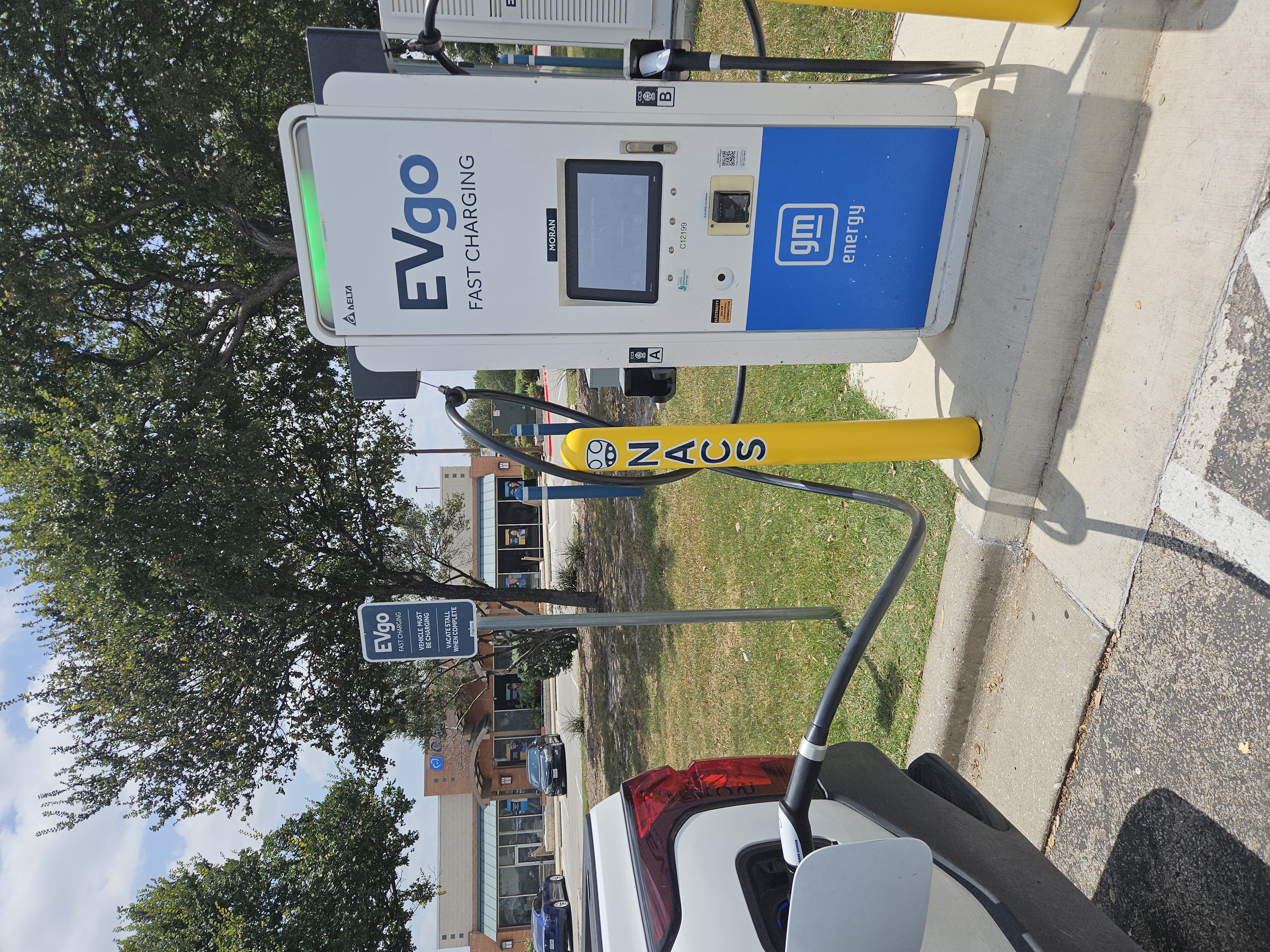 NACS EVgo fast charging unit installed in marked parking space at a public charging station, with EV 