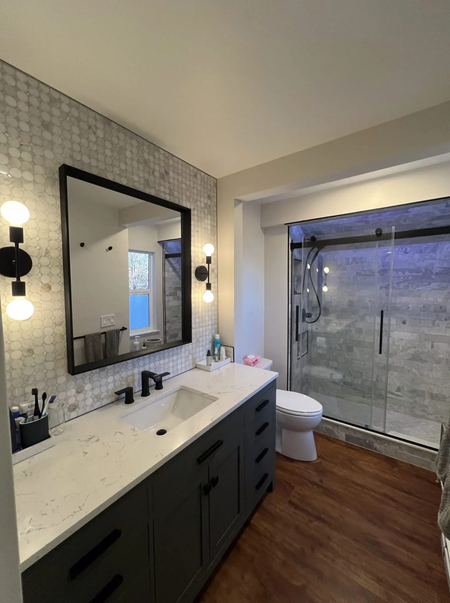 Bathroom renovation featuring a dark wood vanity, stone countertop, and updated fixtures by Elevate Remodels in Gaithersburg, Maryland.