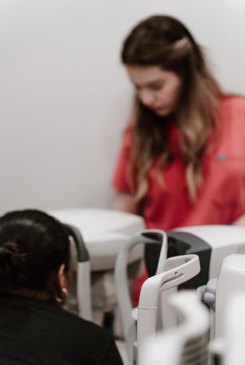 TK Optometry staff member working with eye examination equipment in an optometry exam room in Brookl 