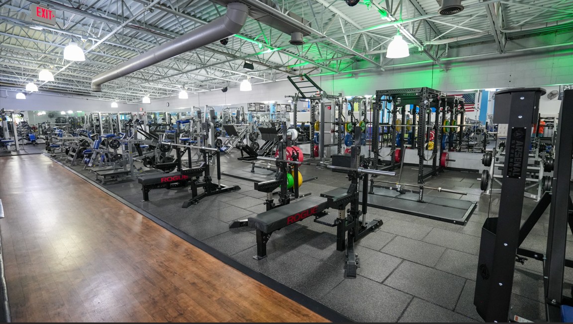 Strength training area at Everyone Fitness Rehoboth Beach featuring Rogue racks, benches, and plate-loaded equipment.