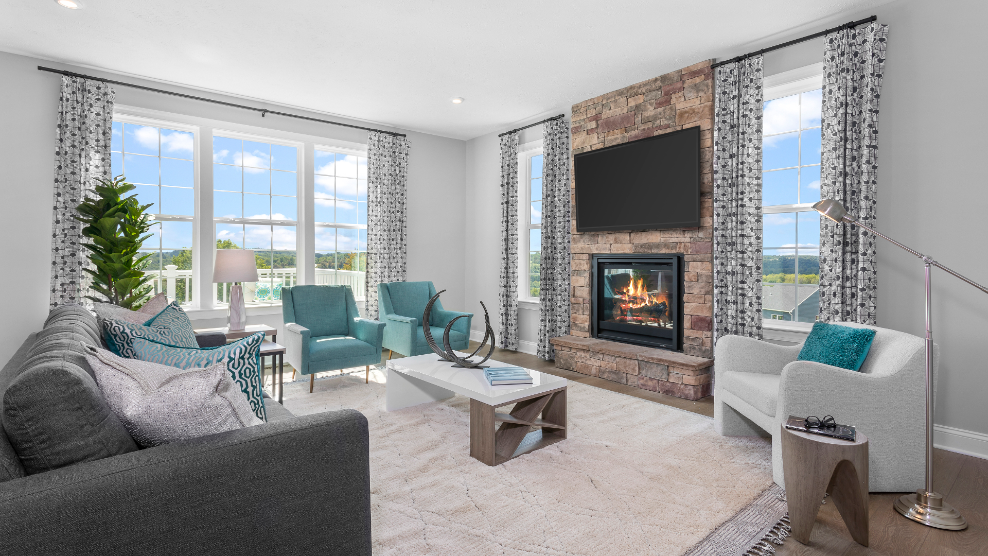 Family room with couch and three chairs, fireplace with TV in DRB Homes Villas at South Park