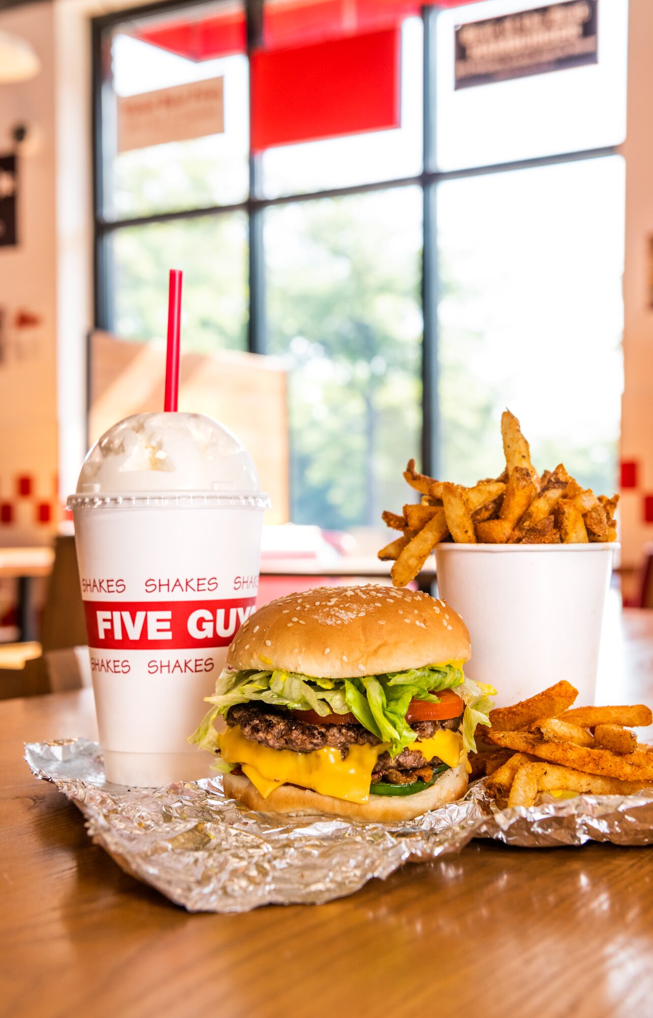 A Five Guys cheeseburger, milkshake and regular order of fries sits on a table inside a Five Guys re Five Guys Ottawa (613)562-8119