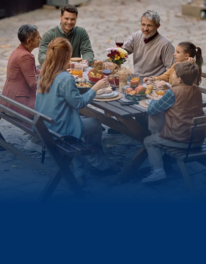 A multigenerational family sharing a meal in a nice backyard setting.
