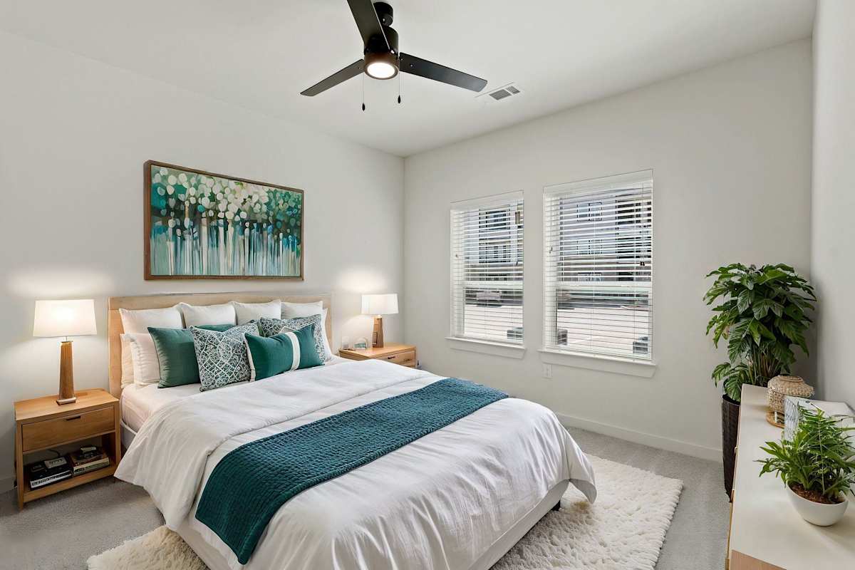 A bedroom with a large bed and a ceiling fan. 