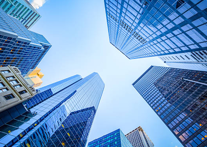 Bottom-up view of skyscrapers with a clear blue sky.