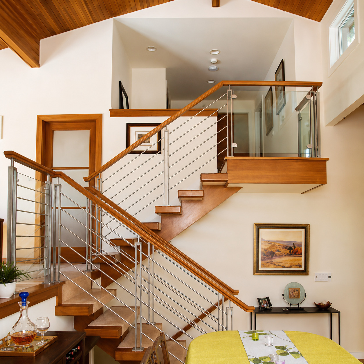 An elegant interior staircase combines warm wooden treads and handrails with sleek metal cable raili 