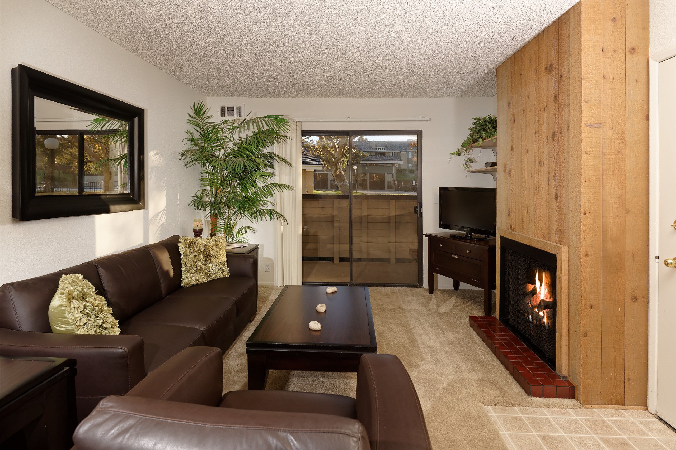 A living room with a brown couch and a fireplace.