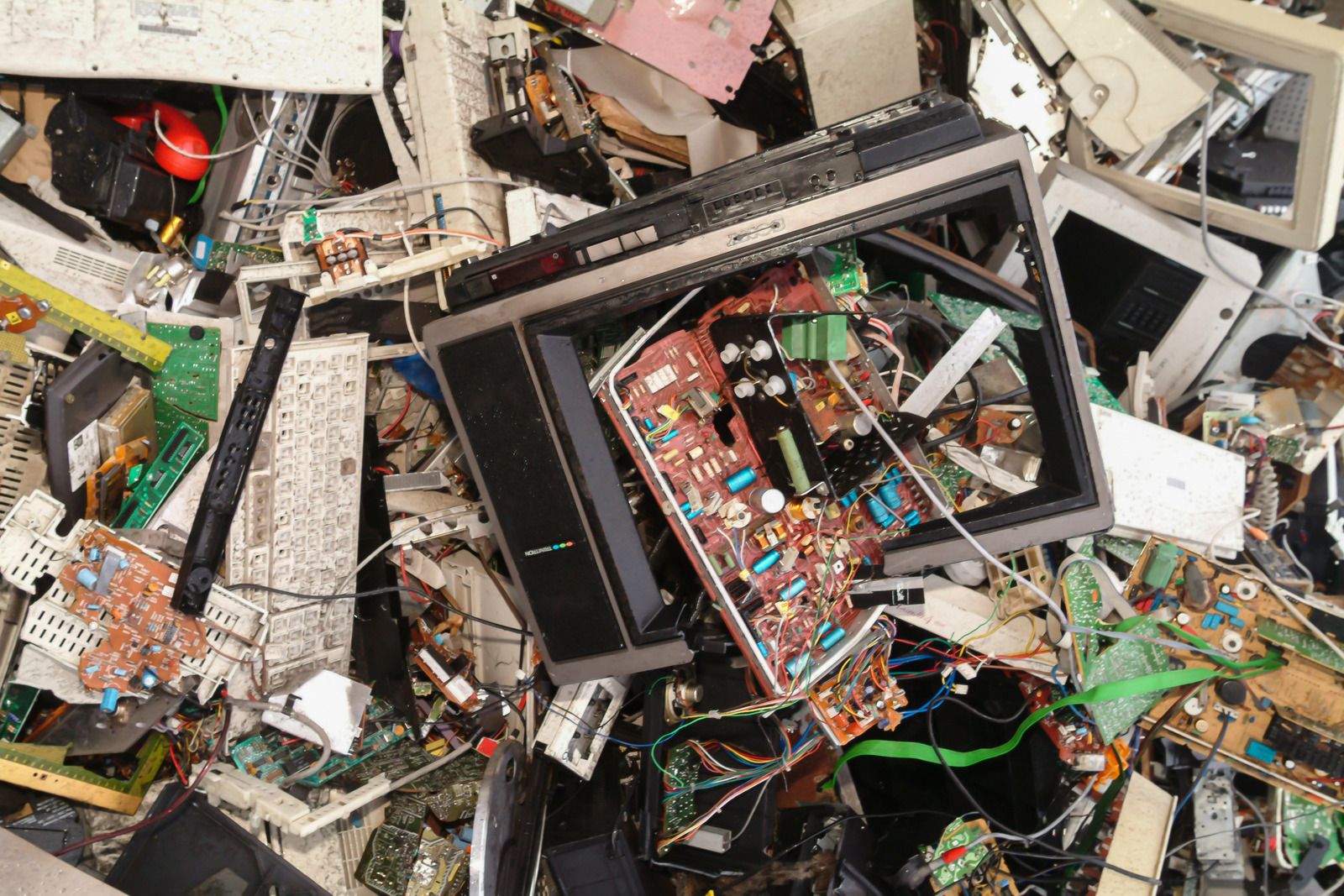 Pile of electronic waste including broken screens, circuit boards, and wiring, illustrating recycling, disposal, and proper handling of discarded electronic materials and components.