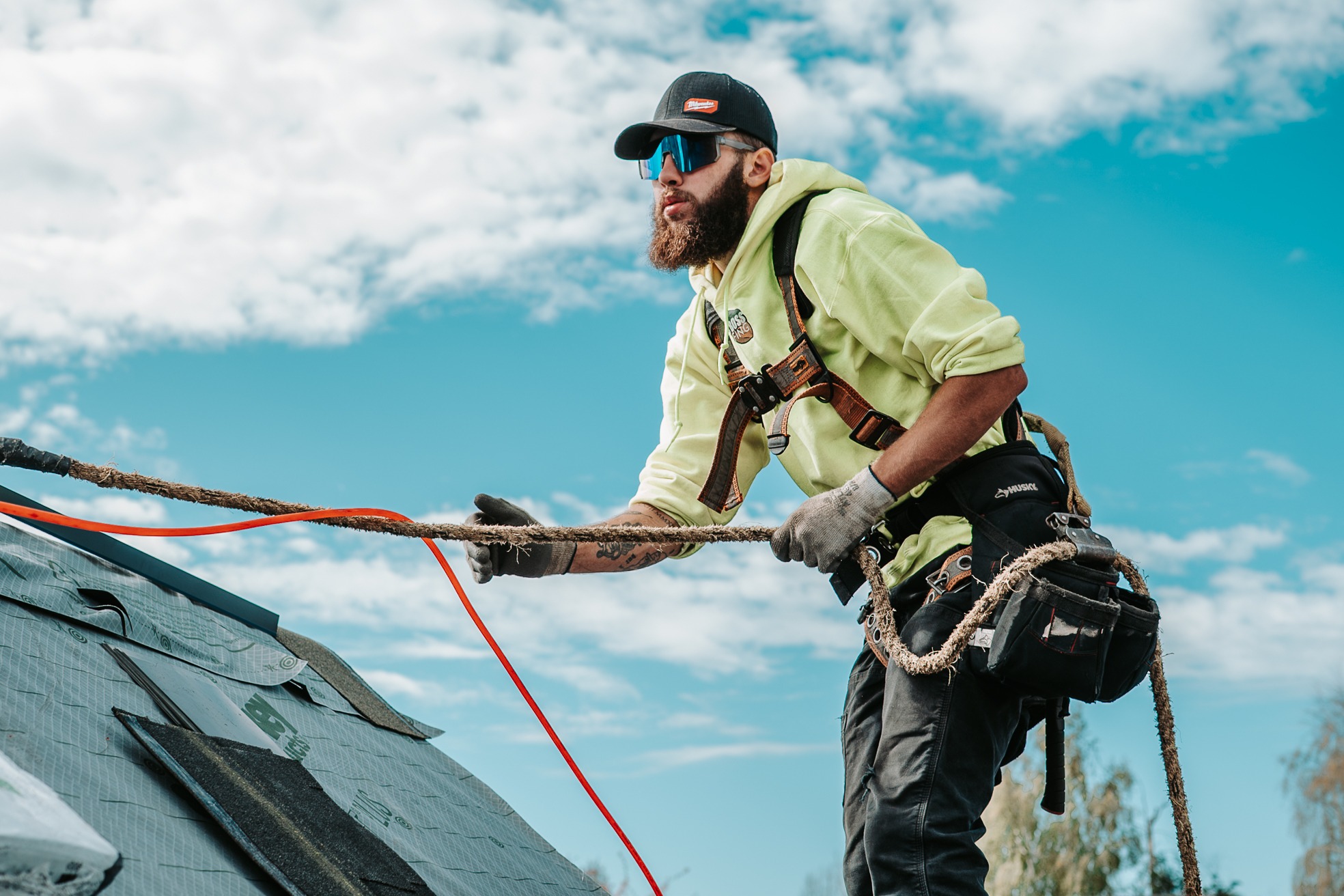 Roofer performing installation work on a residential roof while using proper safety equipment. 