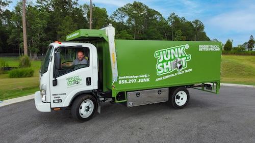 A side-profile shot of the white and green Junk Shot commercial vehicle with the driver looking out  