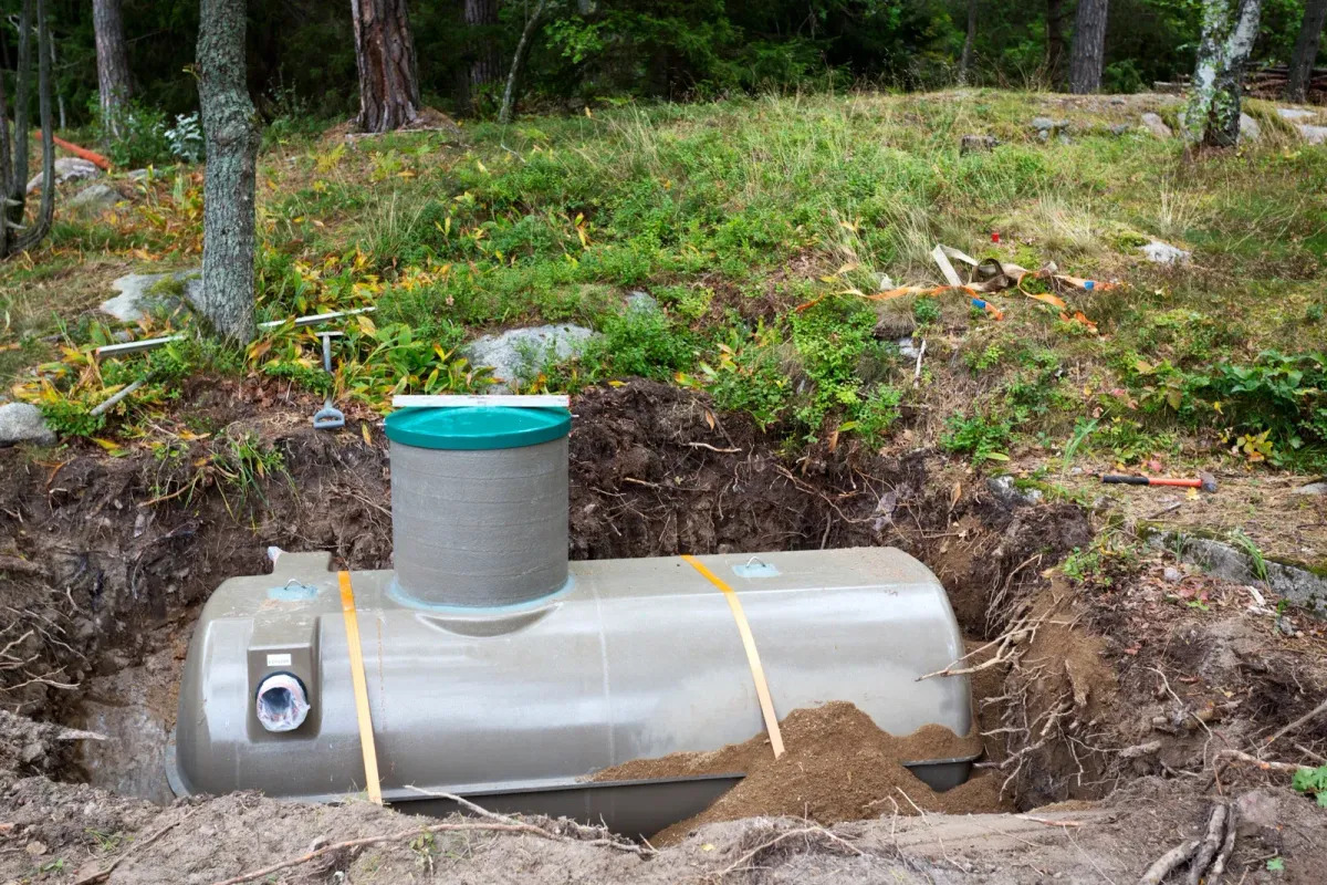 Underground septic tank installation in a rural wooded area with excavation completed for wastewater management. The project showcases professional sitework services including trenching, drainage solutions, utility preparation, and residential septic system placement for reliable property infrastructure.