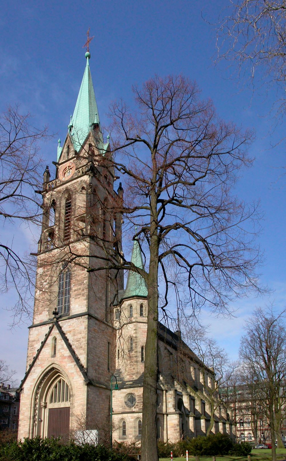 Der neugotische Kirchenbau von 1894 wurde im Krieg 1944 zerstört. Lediglich der Glockenturm blieb nahezu unversehrt. Die Kirche wurde 1952 mit verändertem Innenraum wieder aufgebaut.
Über der Tür in der Eingangshalle begrüßt den Besucher ein Mosaik nach d