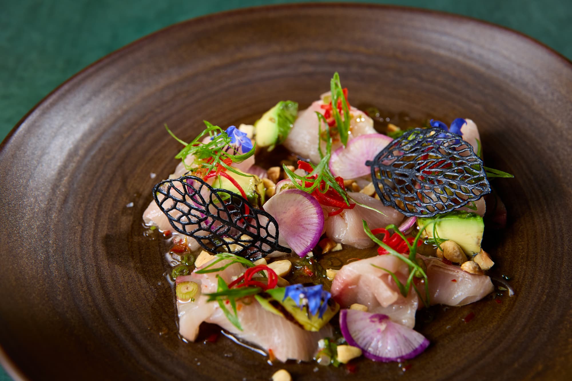 Yellowtail crudo with avocado, radish, and chili garnish at Carversteak NYC.