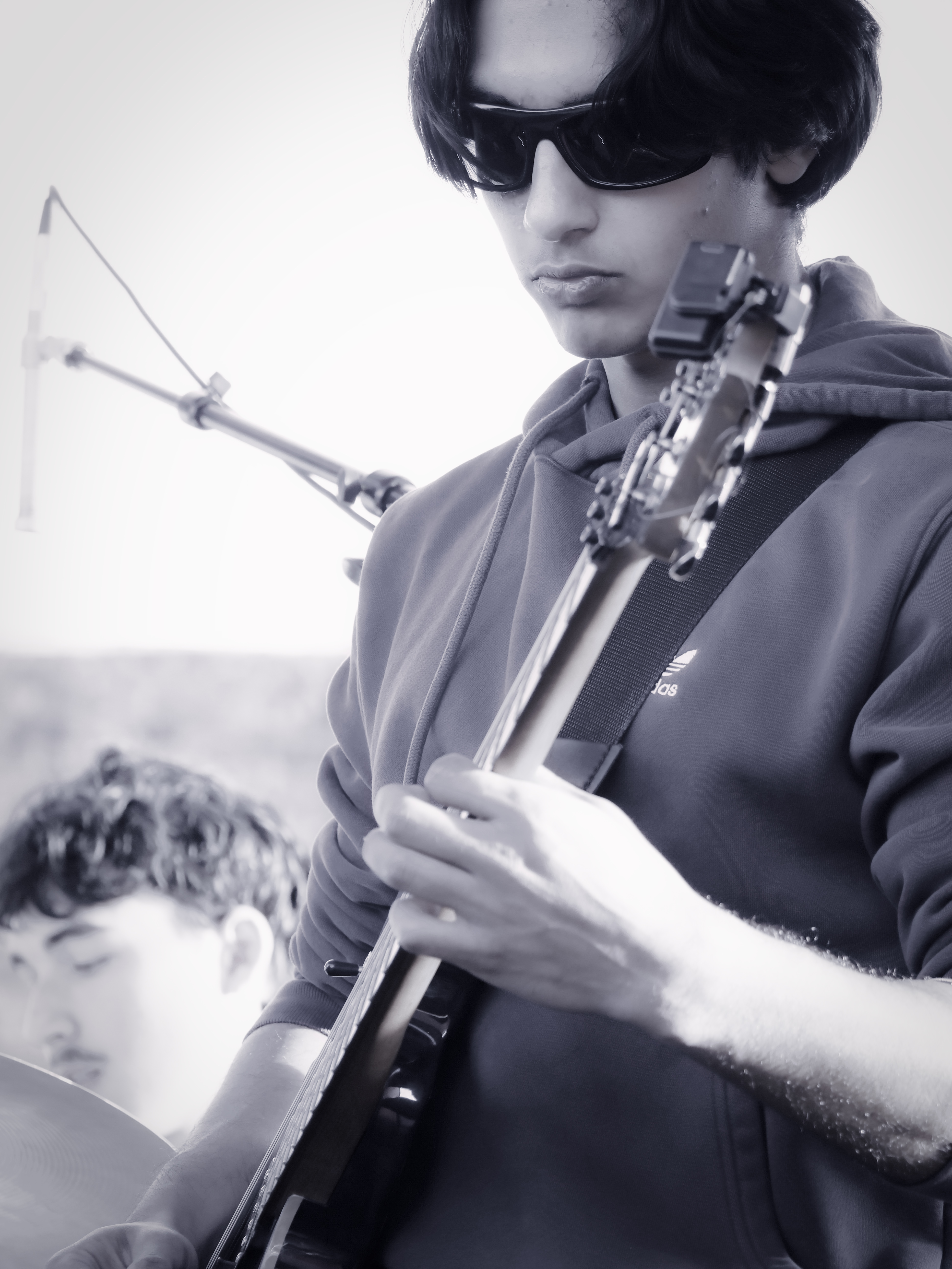 Black-and-white image of a student guitarist playing on stage as part of a live band training session.