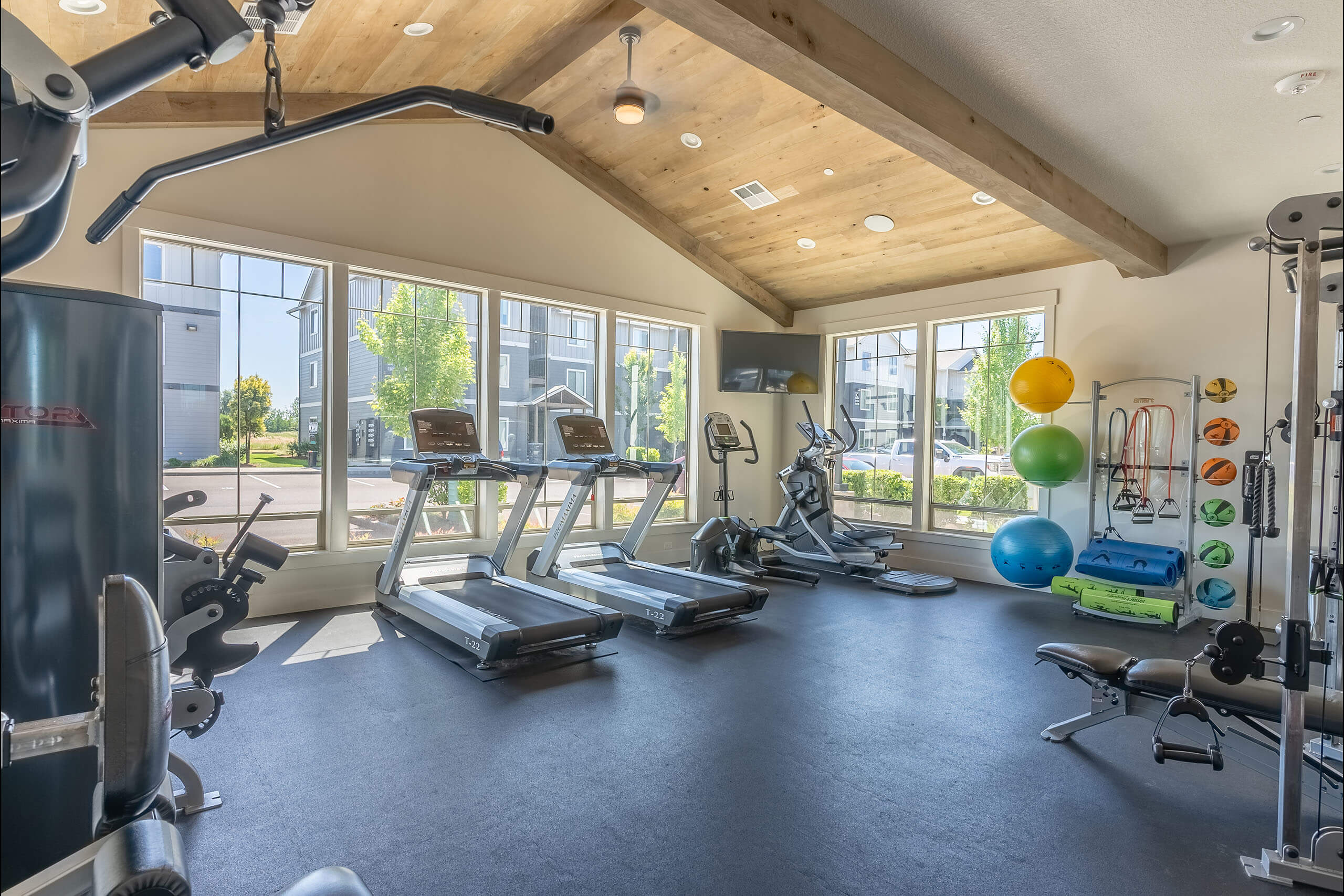 A spacious gym with a variety of exercise equipment and a large window overlooking the outdoors.