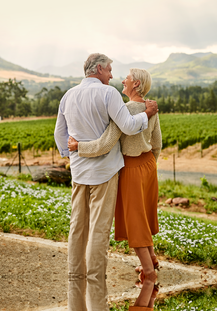 A couple with their arms around each other and a mountain range in the background.