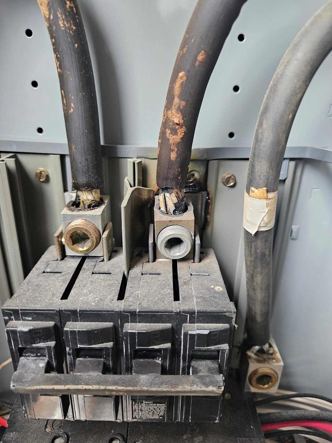Close-up of electrical connections inside panel showing worn insulation on heavy cables, terminals, and connection points, highlighting aging wiring conditions and potential need for maintenance or professional inspection.