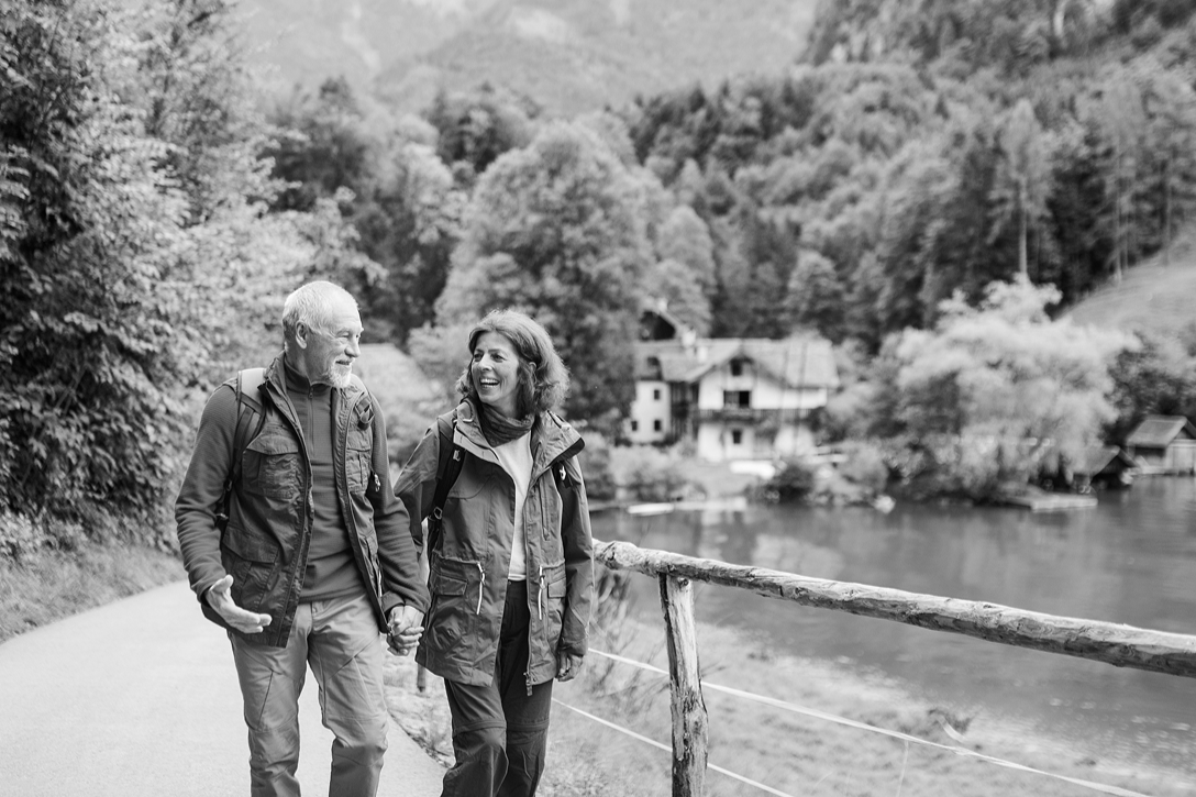 A senior couple hiking in nature, holding hands.