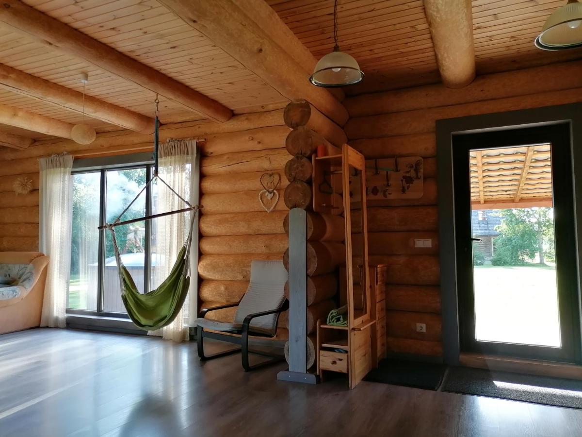 Gaiša un mājīga guļamistaba viesu namā 'Palmas' ar komfortablu gultu, koka detaļām un logu ar skatu uz dabu.
