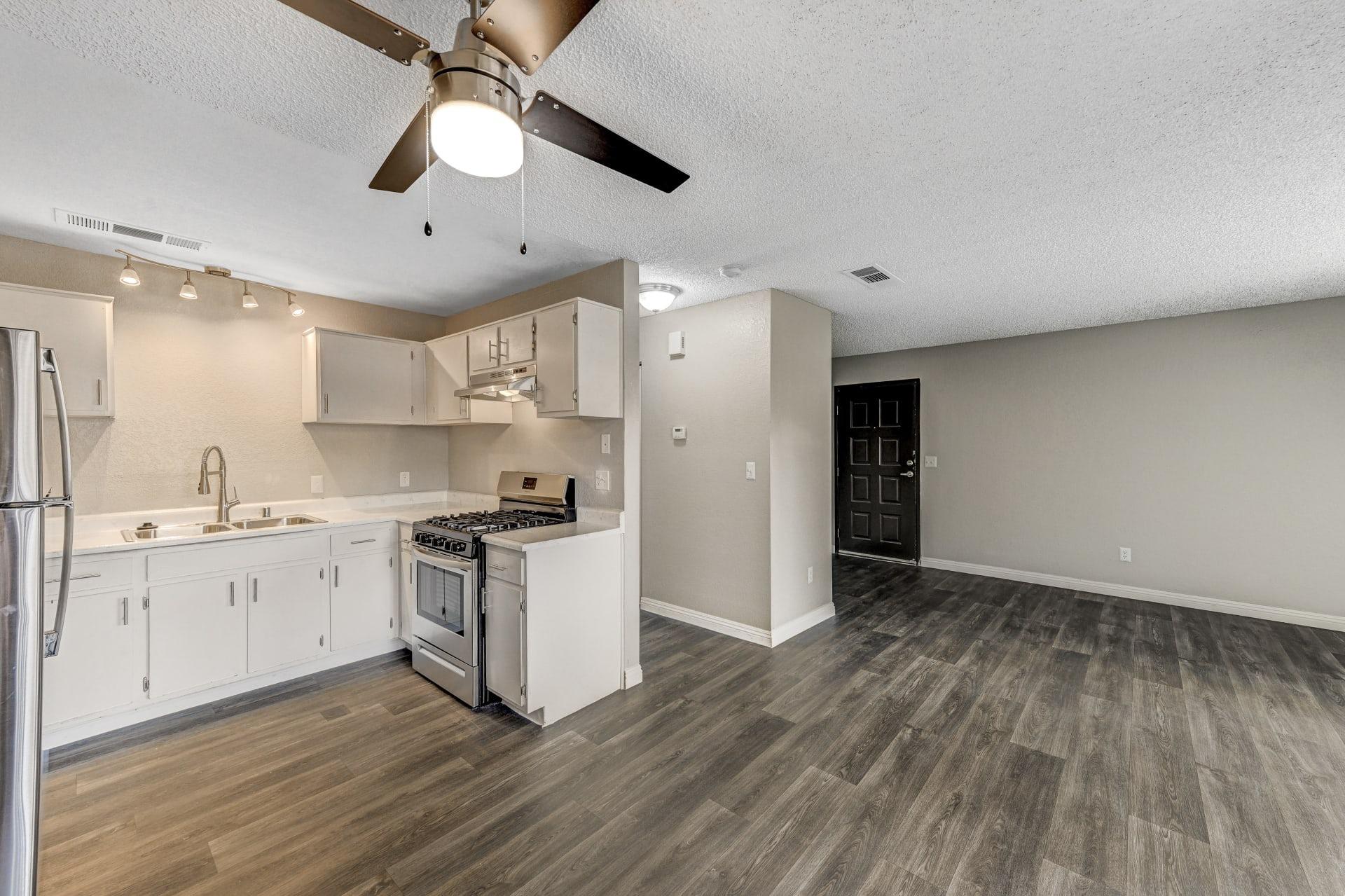 Open kitchen with updated flooring and ceiling fan