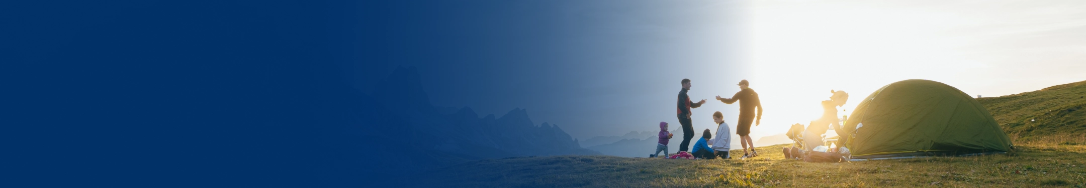 Two young families setting up camp together on the side of a mountain.