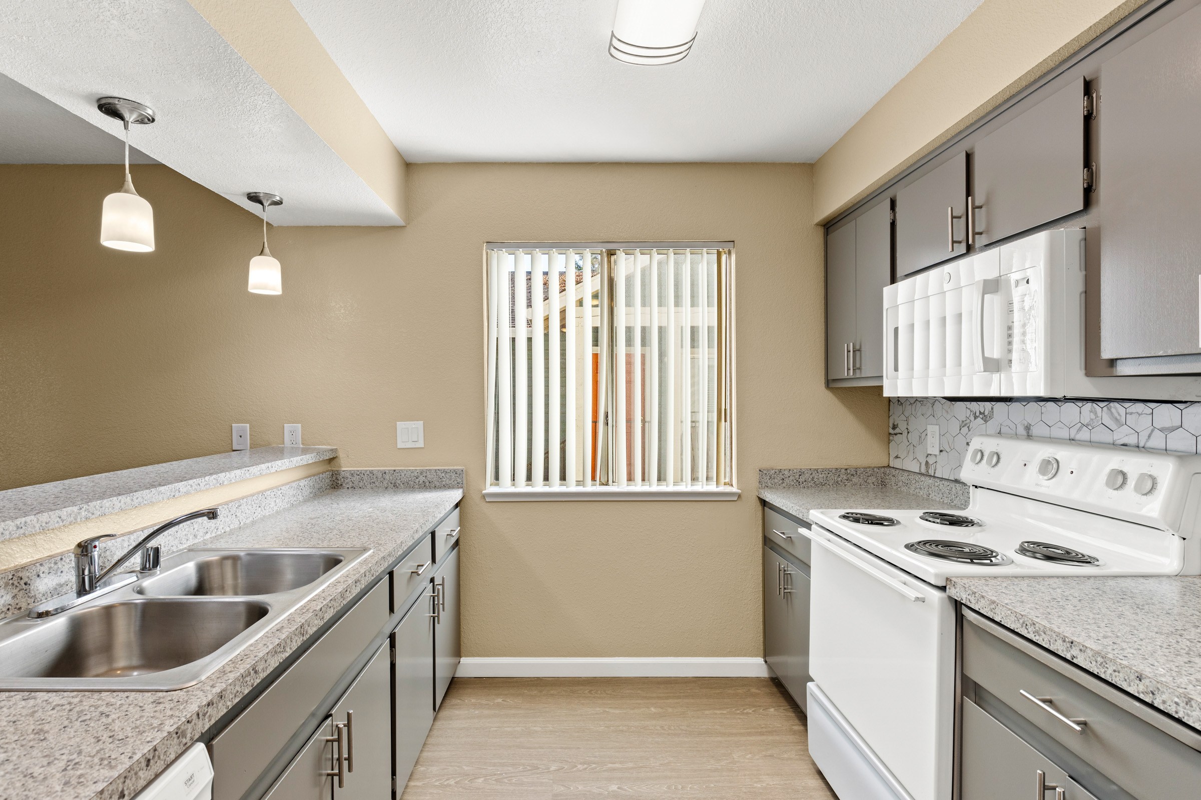 A kitchen with a stove, sink, and cabinets.