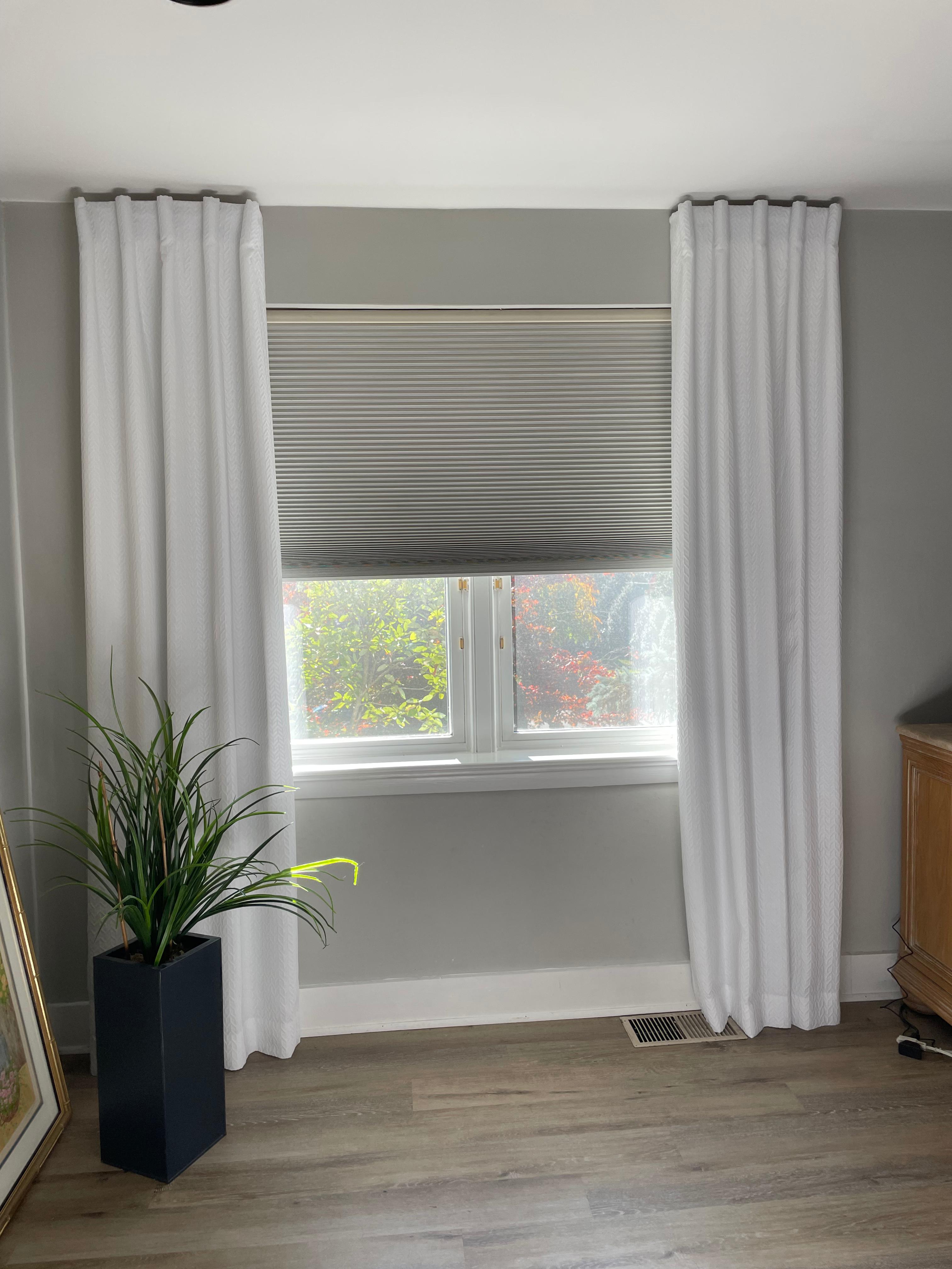 Beautiful neutral window shades with luxurious white drapery.