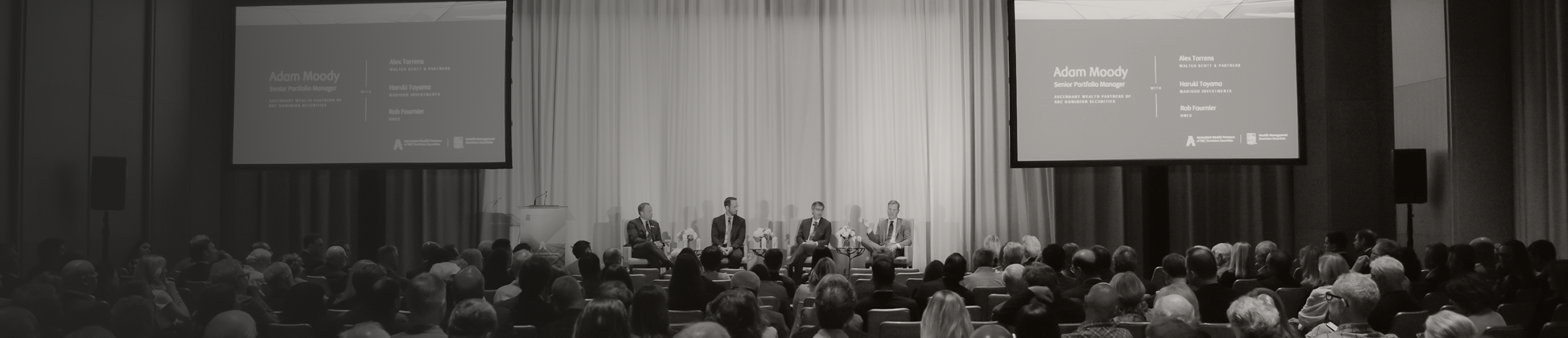 Senior Portfolio Manager, Adam Moody, on stage moderating a panel of wealth management experts in front of a large audience.