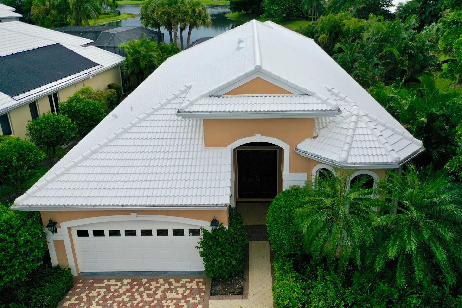 an aerial view of a house with a white roof surrounded by trees.
