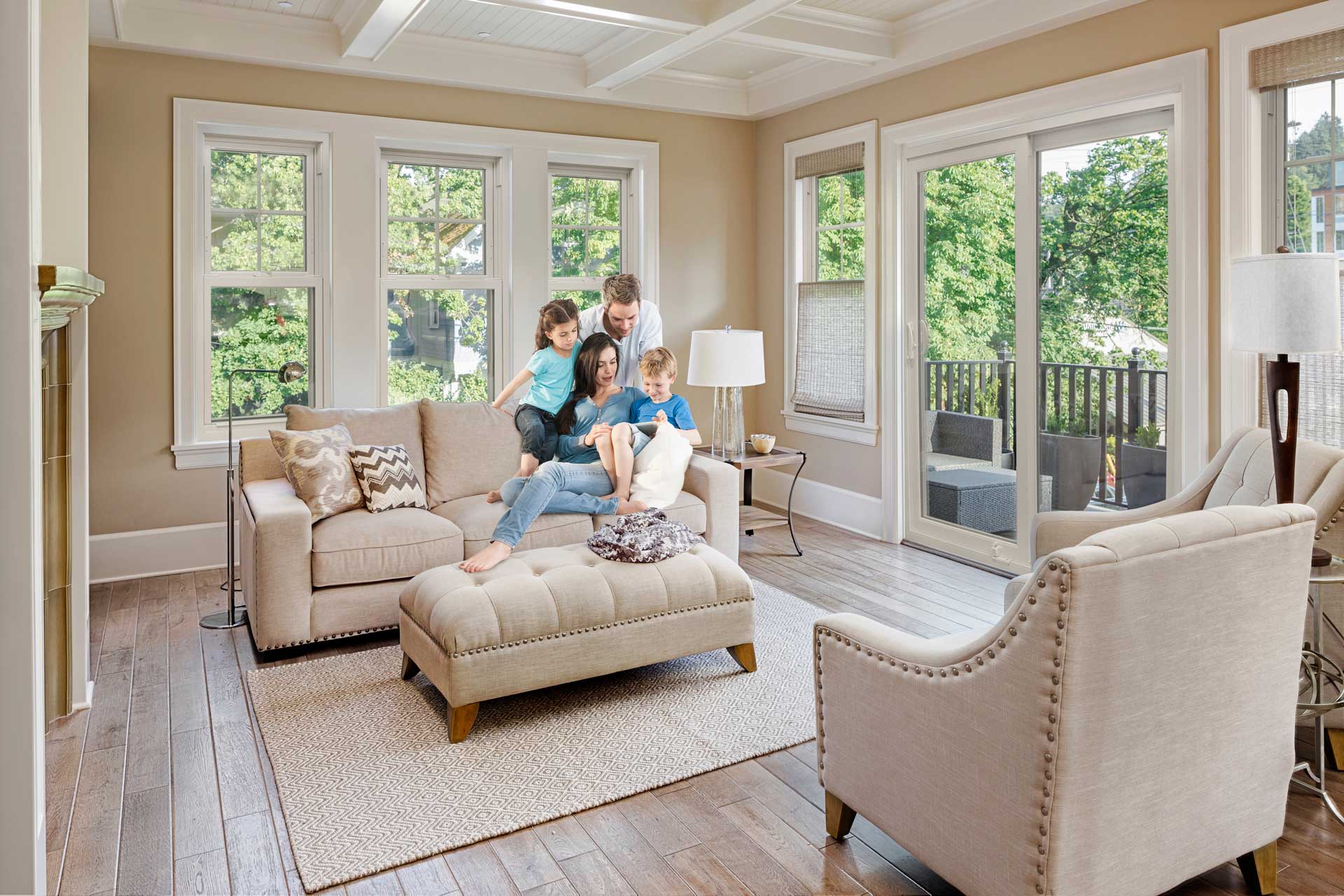 The EcoTek 3200 Series Double-Hung Window in this living room opens up to a beautiful outdoor space, filling the room with natural light. Its classic design seamlessly blends with the cozy, neutral decor, creating a warm and inviting family-friendly atmosphere that is both stylish and functional.
