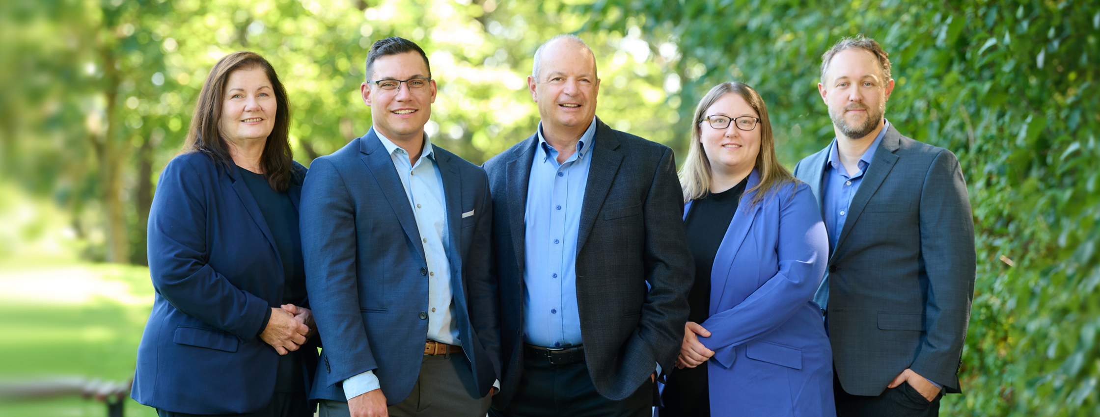 The Balfe Martin Private Wealth team standing together surrounded by greenery.