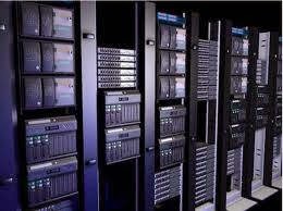 A rack of servers in a data center, with multiple rows of equipment visible. The servers are black and grey, with some blue and green indicator lights. The overall impression is one of a highly organized and technical environment.