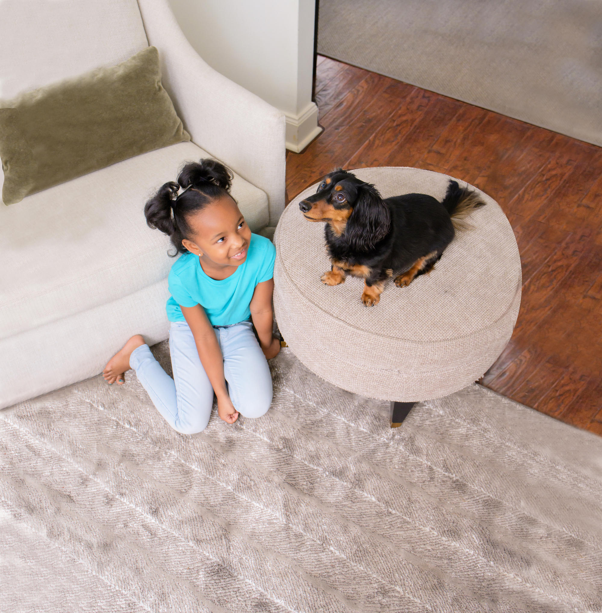 Young girl and her dog sitting next to upholstered furniture in Anaheim